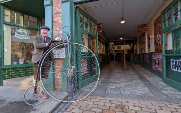 Ian Bean with Penny Farthing outside the garage at Beamish Museum - Vote for Ian Bean for Durham Tourism Superstar 2023!