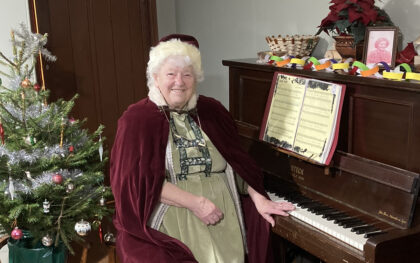 Mrs Claus playing festive songs at Orchard Cottage, 1940s Farm at Beamish Museum